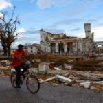 A man rides a bicycle in front of the damaged St. Elizabeth Parish Court in the aftermath of Hurricane Melissa, in Black River, Jamaica, November 5, 2025. REUTERS/Raquel Cunha